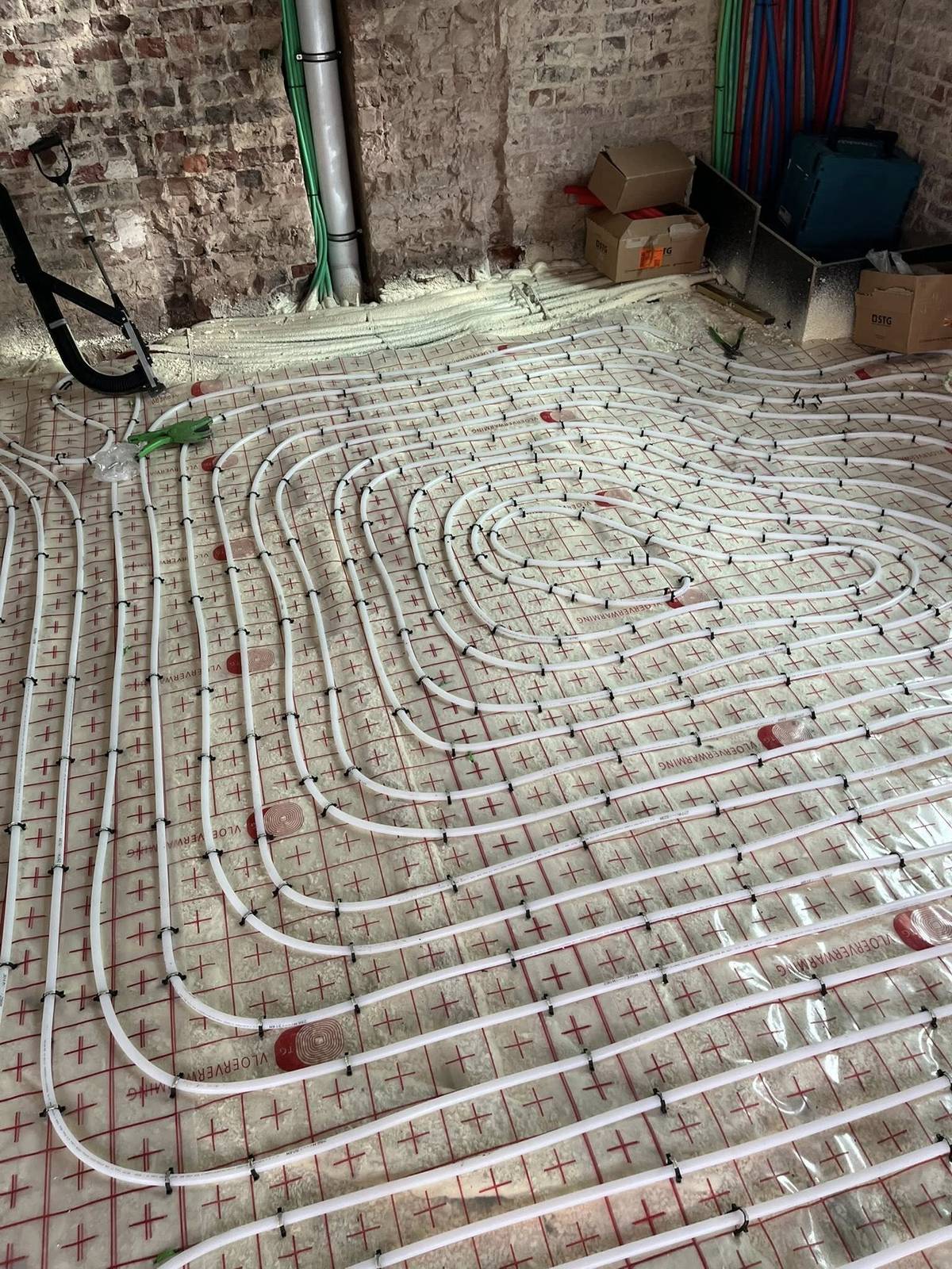 Installatie van vloerverwarming met een patroon van buizen op een bouwvloer