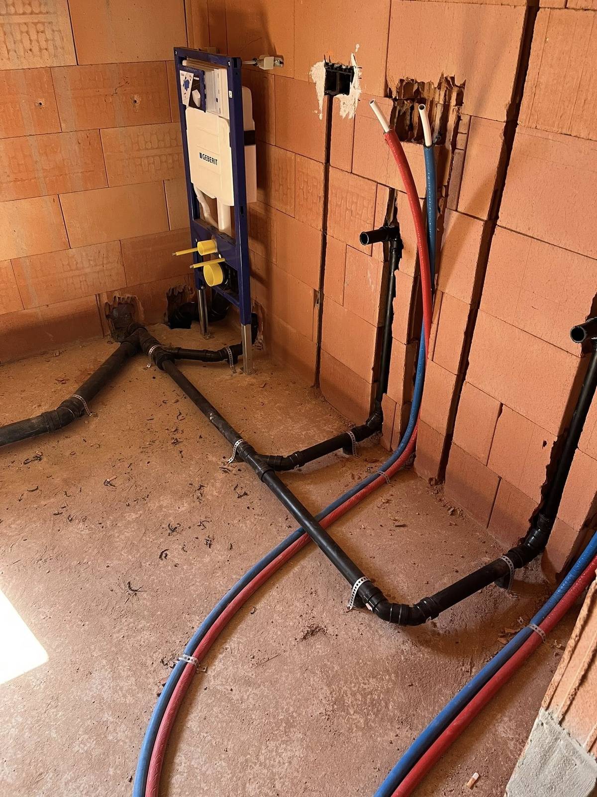 Voorbereiding voor een zwevend toilet met afvoer- en watertoevoerleidingen in een onafgewerkte badkamer