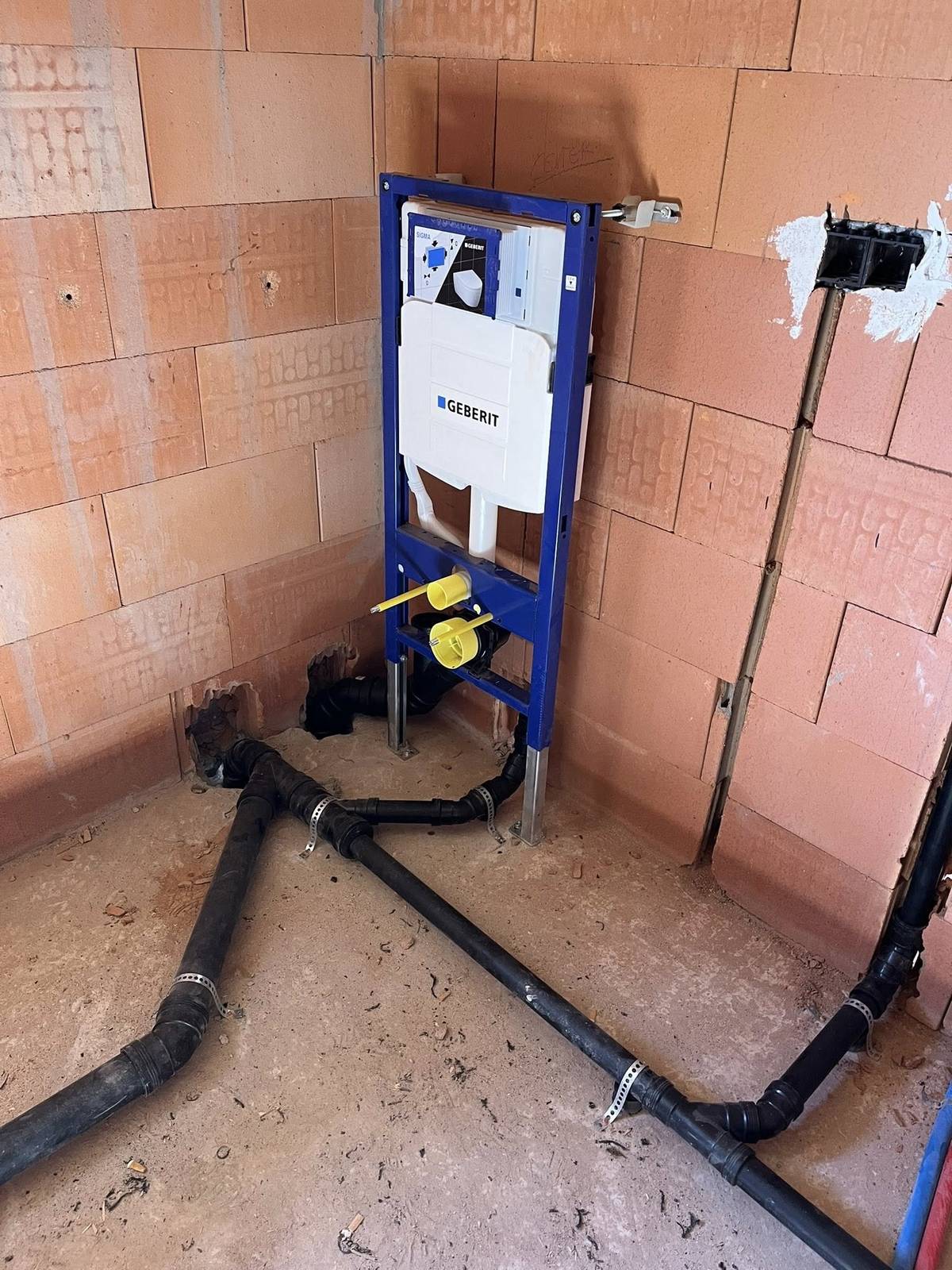 Voorbereiding voor een inbouwtoilet met Geberit frame en afvoerleidingen.